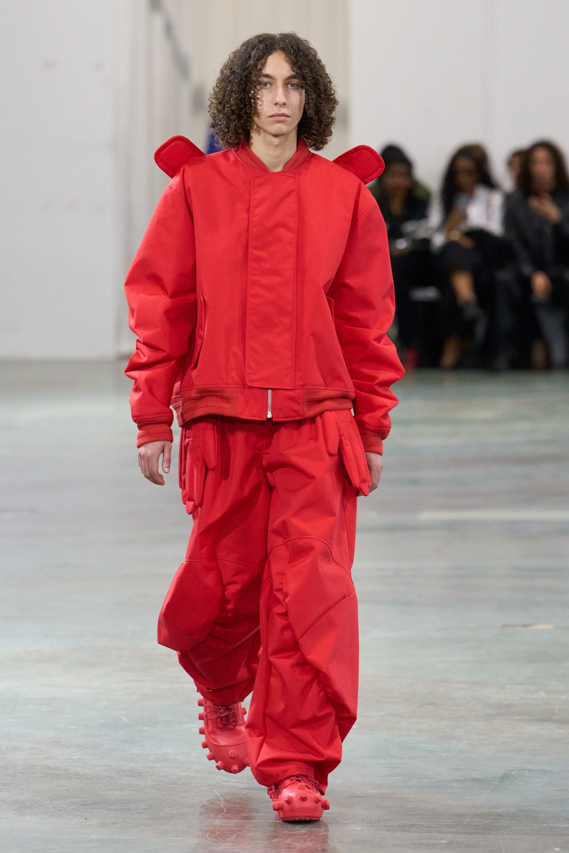 Walter Van Beirendonck 2026秋冬以高度饱和的色彩、夸张比例与童真符号继续挑战男性气质的既定边界。针织花朵、卡通图案、结构化西装与机能裤装并置，构建出介于游戏、政治隐喻与乌托邦幻想之间的舞台。系列拒绝低调，刻意制造视觉噪音，用快乐、怪诞与不合时宜的色彩作为对现实焦虑的反击，呈现一场毫不妥协的时装宣言-顽石频道趋势研究